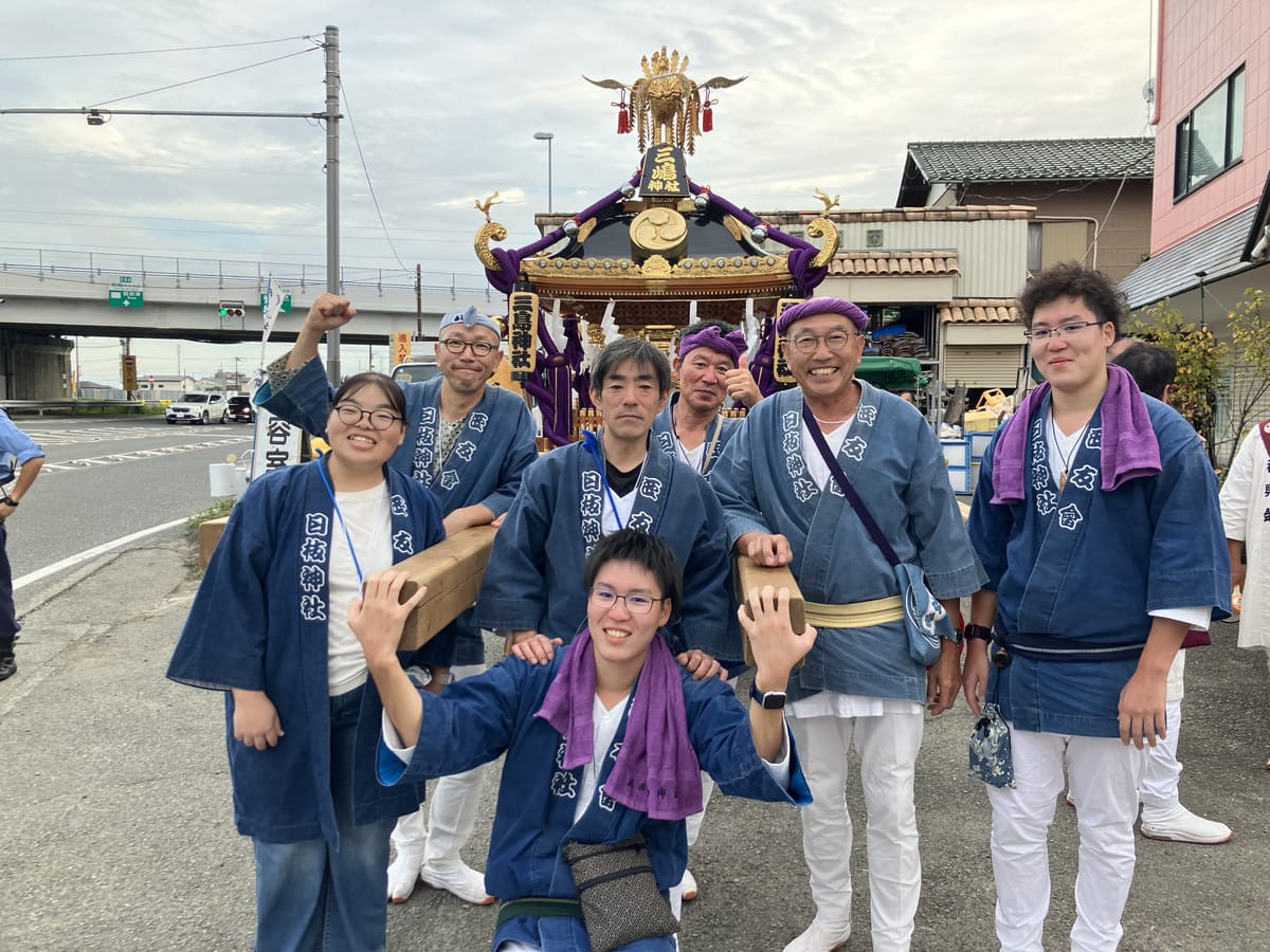 三嶋神社の神輿の前で、そろいの半纏を着た担ぎ手の集合写真
